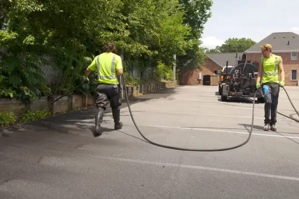 Workers applying spray coat on pavement