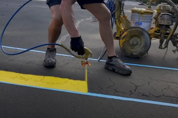 Man painting yellow line on pavement